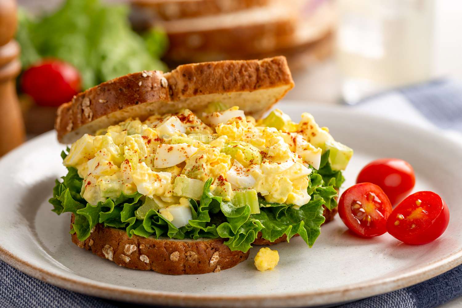 Egg salad sandwich with lettuce on whole grain bread and grape tomatoes on a plate