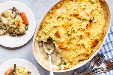 Vegetarian Shepherd’s Pie Recipe -- top down shot of shepards pie scoop taken out, golden and crispy edge mashed potatoes on top. Blue check table cloth, and a plate with some sheperd'e pie serve on top of it.