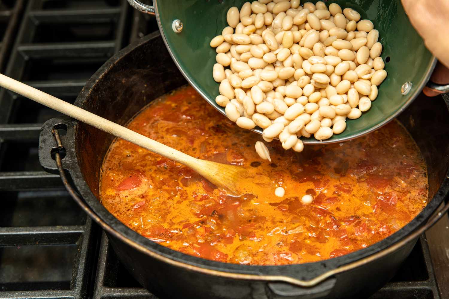 Beans Added to Spaghetti Squash Soup with Italian Sausage in a Cast Iron Pot on a Stove