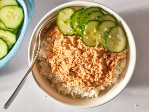Rice bowl topped with spicy tuna and sliced cucumber, fork on the side.