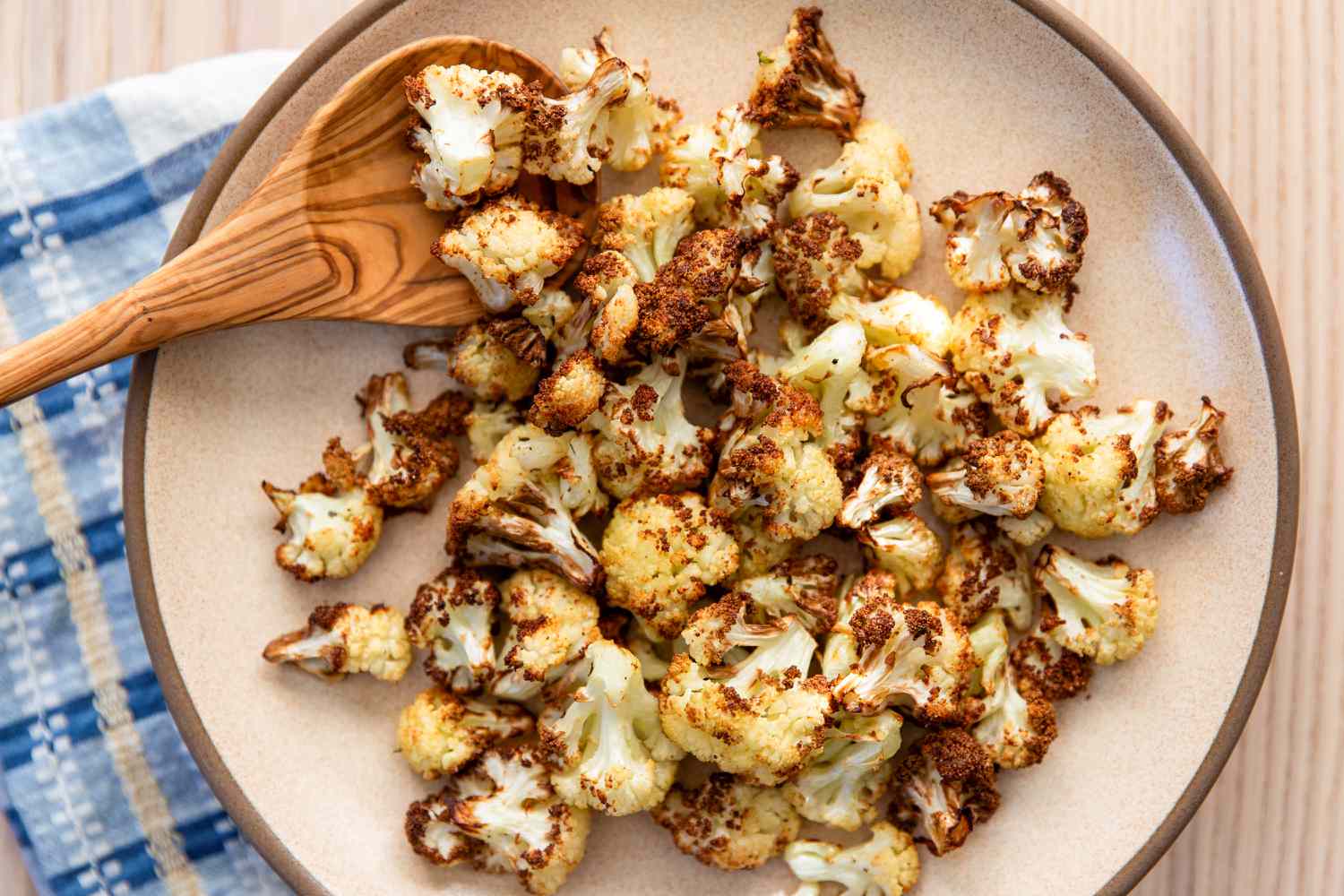Garlicky Air Fryer Cauliflower on a plate with a wooden spoon