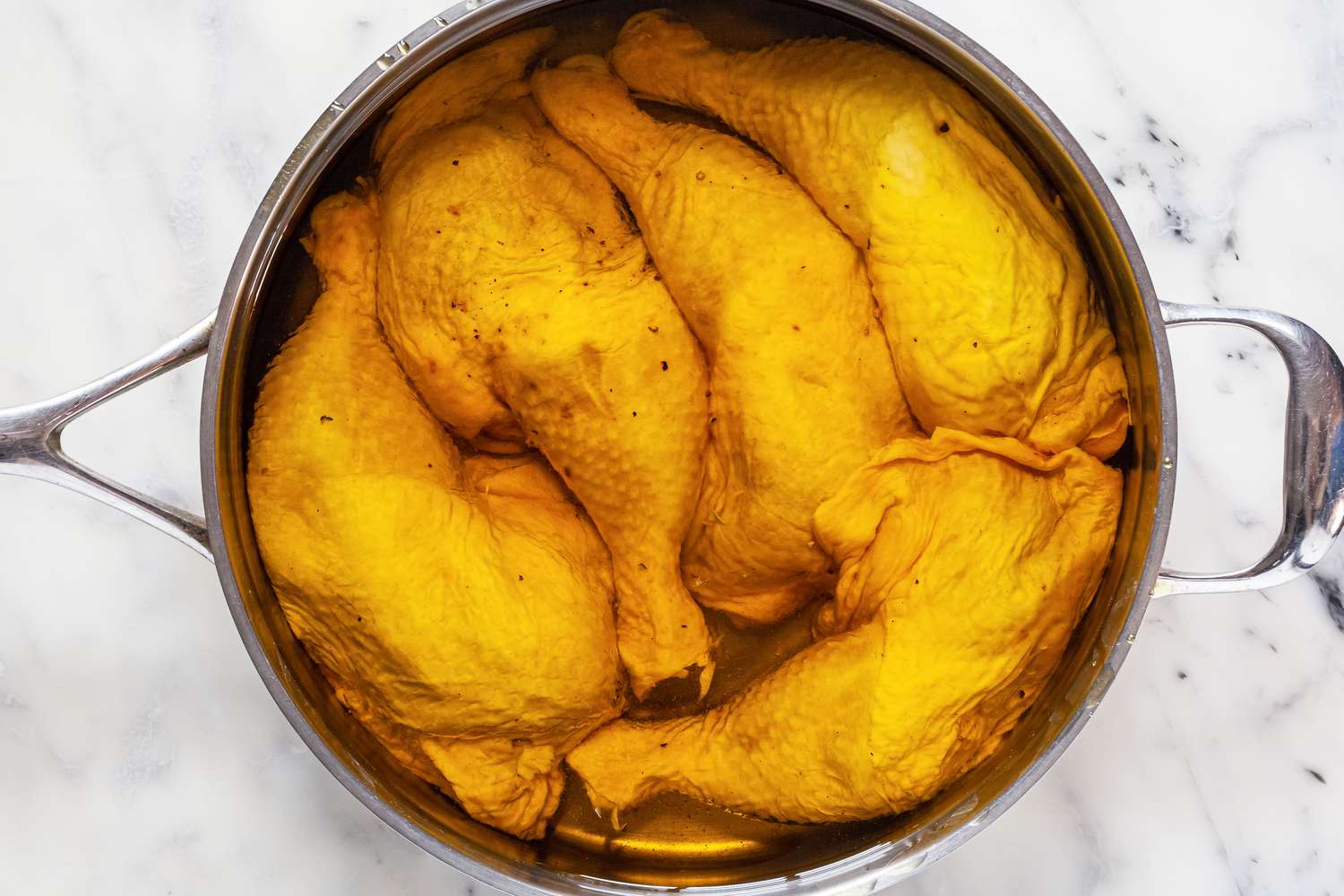 Whole chicken legs in olive oil.