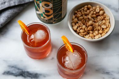 Overhead view of two Negronis with non alcoholic gin, bar nuts and an orange wedge.