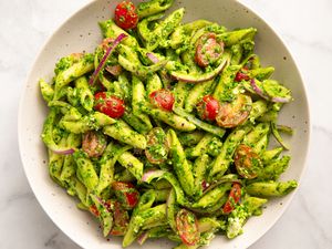 Pasta with cherry tomatoes spinach feta cheese and pesto in a bowl