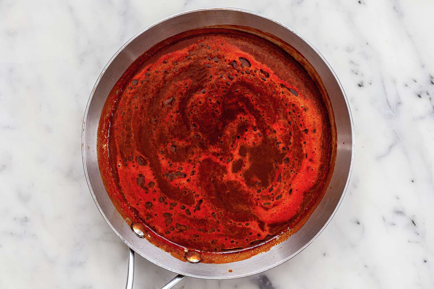 Simmering red chili sauce in a pot.
