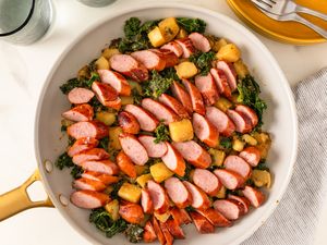 Skillet with sliced sausage potatoes and kale arranged neatly