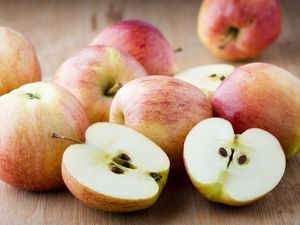 Various whole and halved apples arranged on a wooden surface