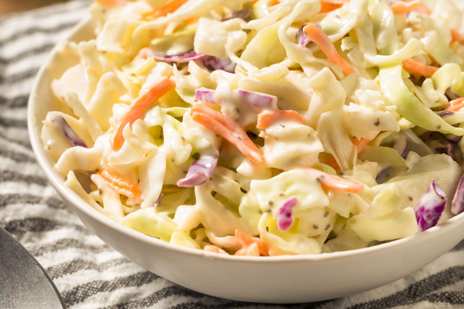 A close up picture of coleslaw on a striped napkin. 
