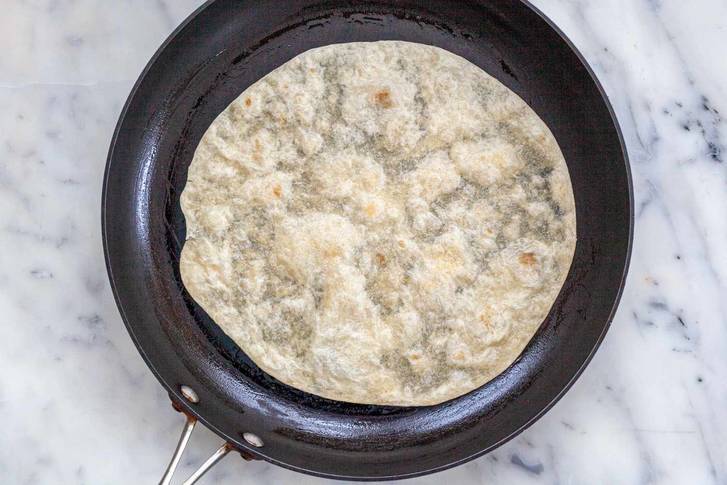 Frying a tortilla in a skillet to make quesedillas.