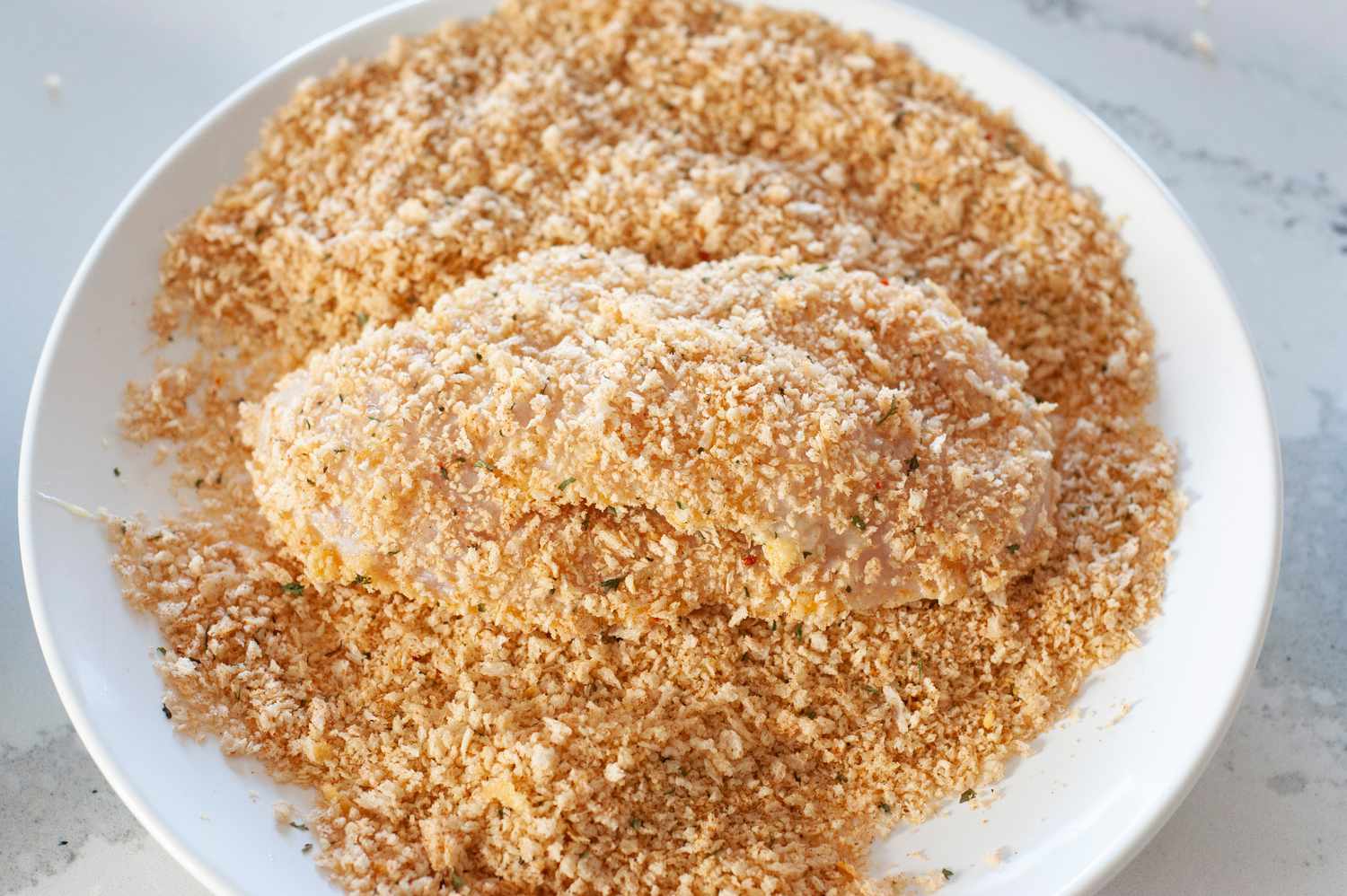 Dredge breadcrumbs on chicken.
