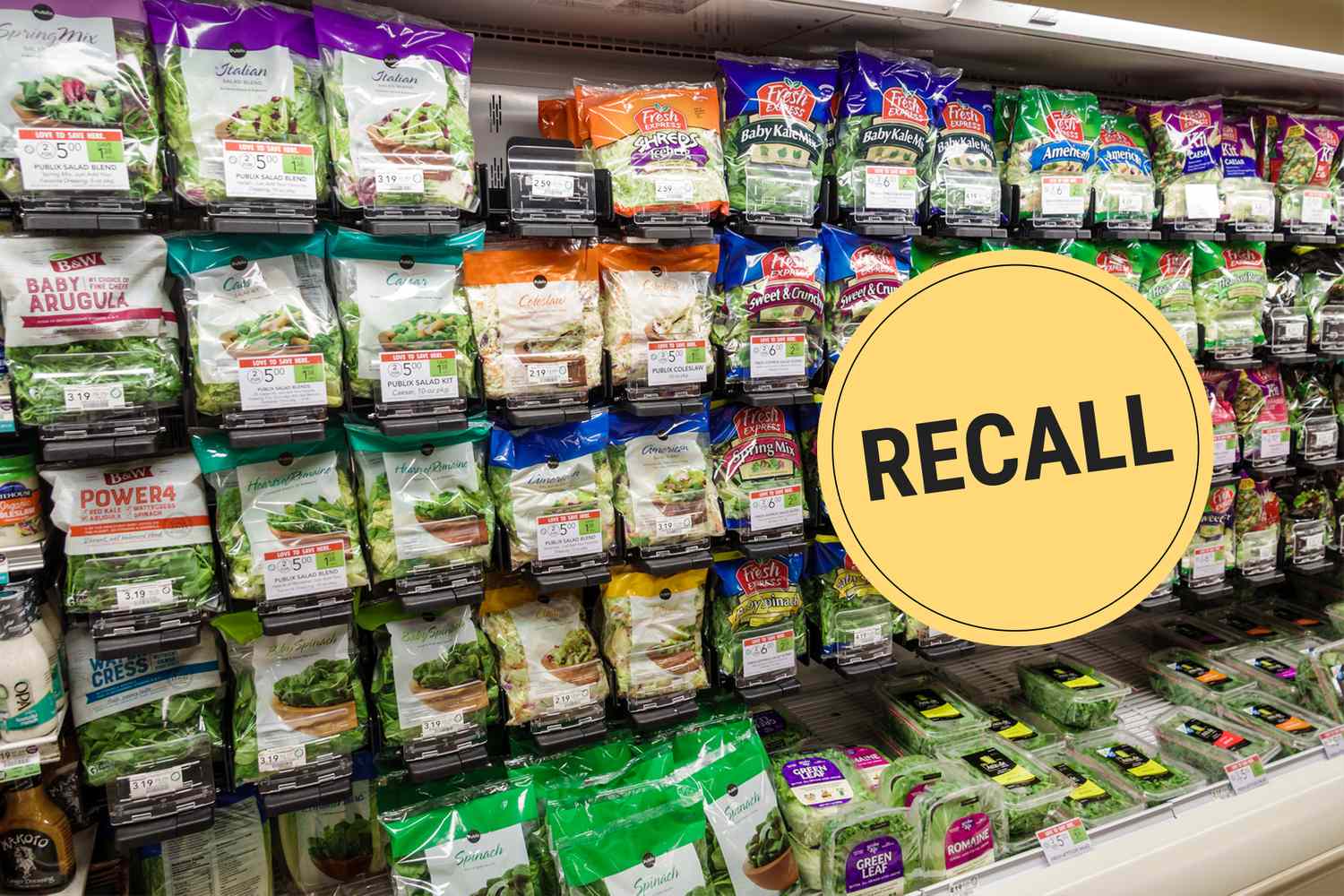 Supermarket shelf stocked with packaged salad kits yellow recall sign placed above products