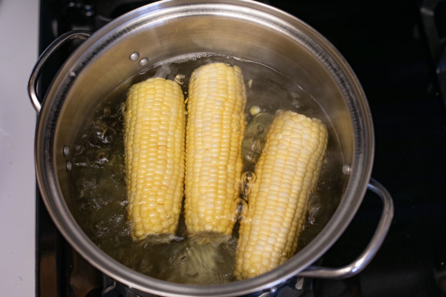 Ears of corn boiling in a pot of water