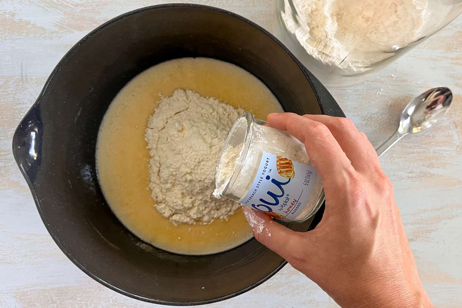 Yogurt cup used to measure and pour dry ingredients into the bowl of wet ingredients