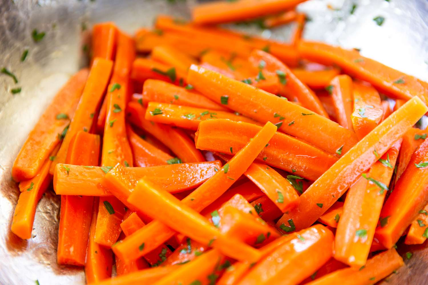 Closeup of julienned carrots tossed in herbs