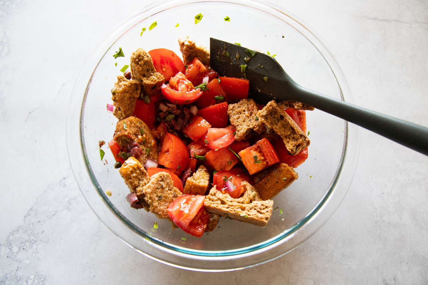 Bread and tomatoes mixed in a bowl to make a summer vegetable salad with feta