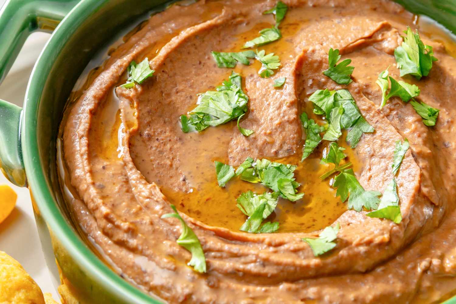 A bowl of black bean dip garnished with chopped parsley