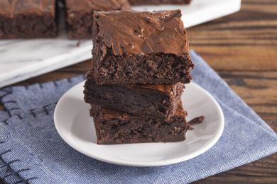 Stack of homemade double chocolate brownies on a saucer on top of a blue cloth napkin