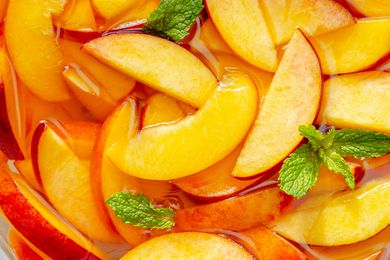 Sliced peaches and mint in a liquid, a fruit preparation for a recipe