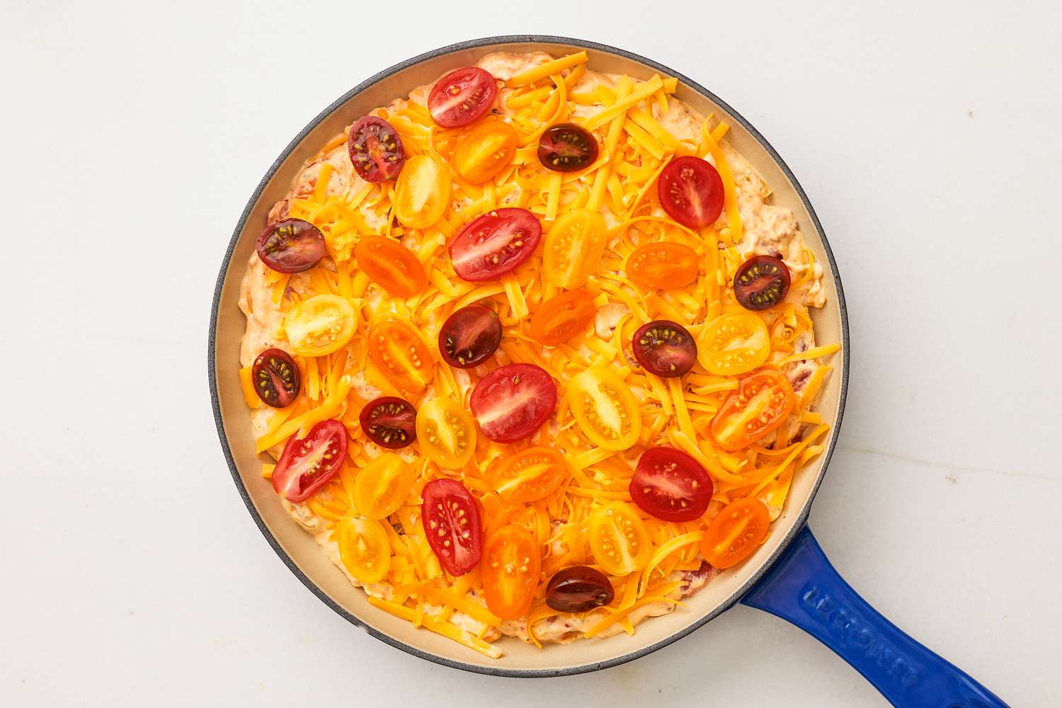 tomato pie dip filling topped with more cheddar and grape tomato halves