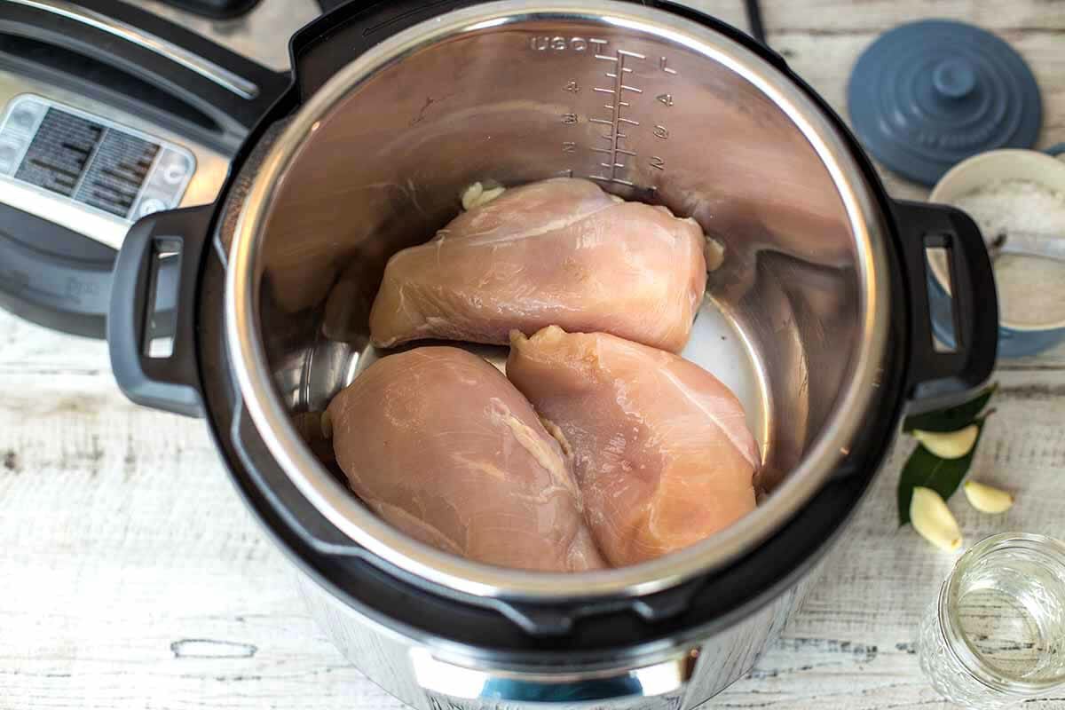 three raw chicken breasts placed in the instant pot