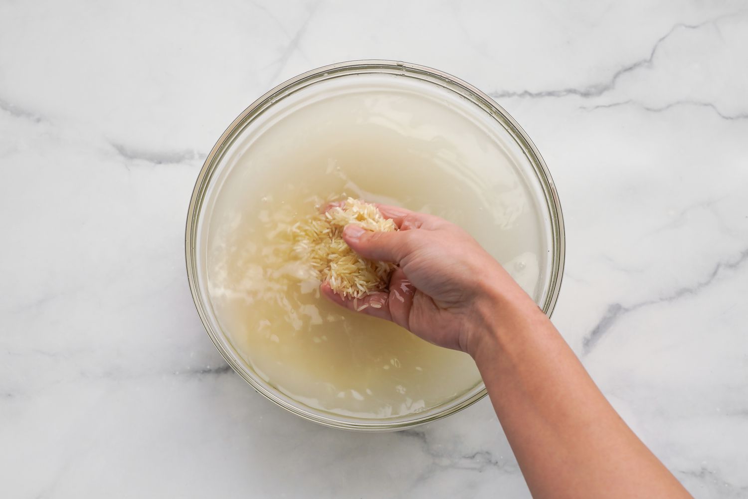 A Hand Washing Basmati Rice in a Bowl of Water for Sabzi Polo Recipe