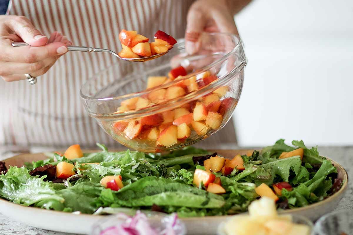 Salad recipe with peaches, goat cheese, and pistachios plate the salads