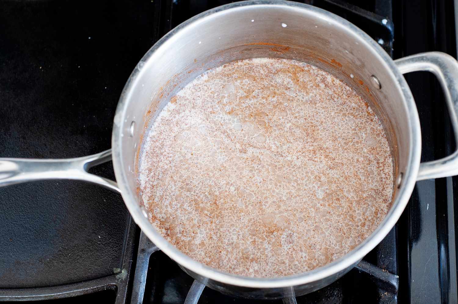 Cinnamon and cream mixed in a tall sided skillet to make cinnamon ice cream.