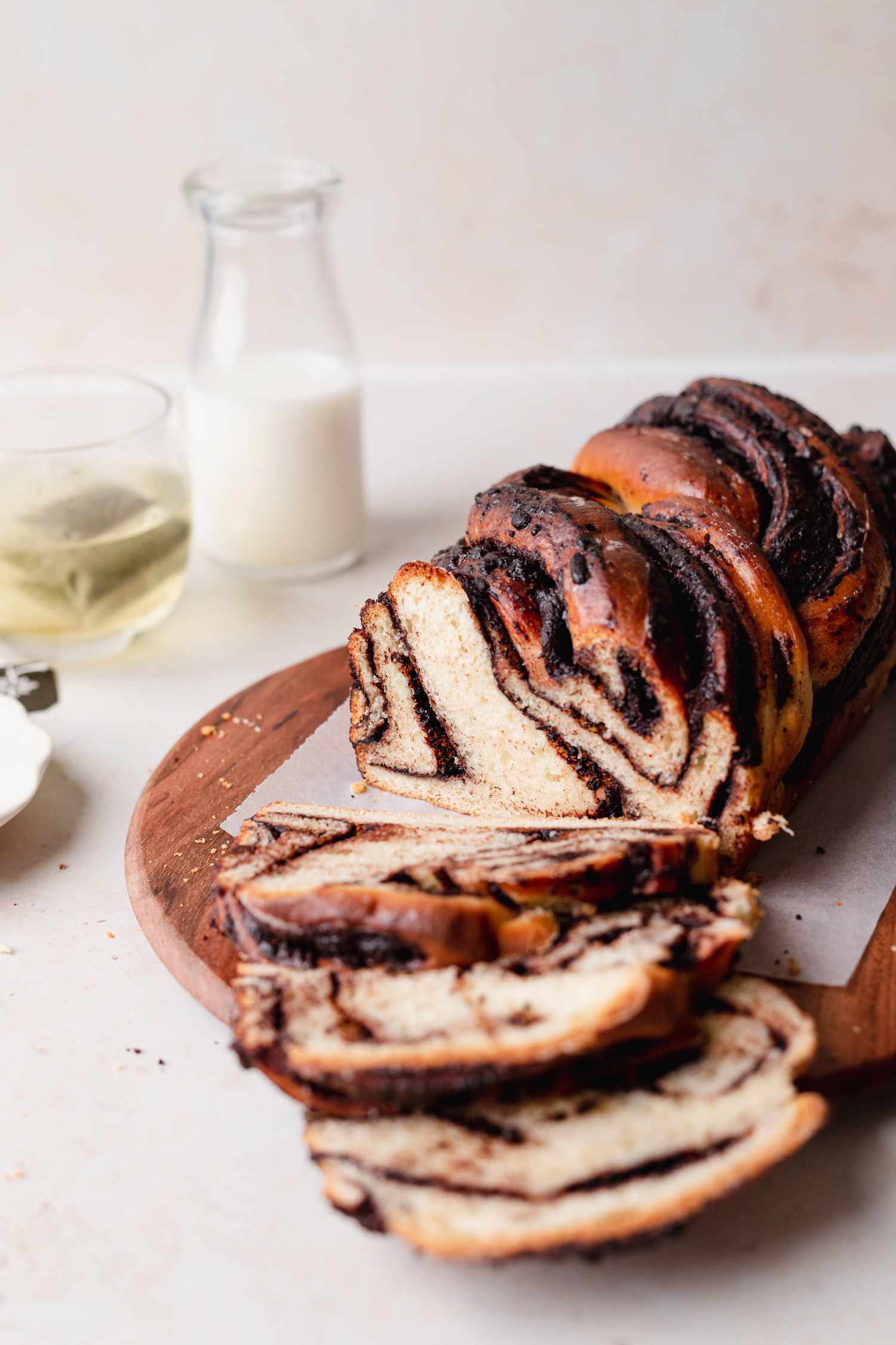 Braided chocolate babka with a couple slices laid in front of the whole loaf on a cutting board.