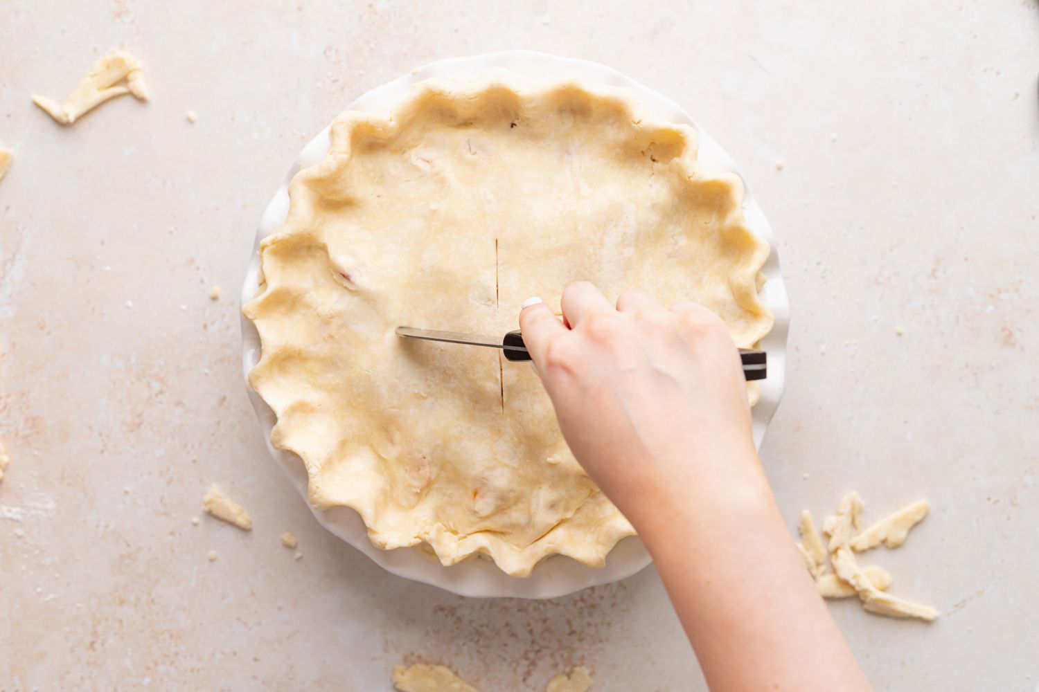 Scoring an easy peach raspberry pie before baking.