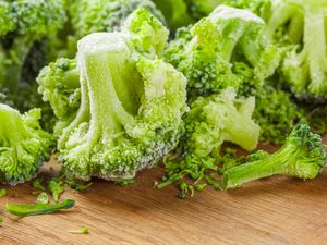 Frozen broccoli florets on a wooden surface focus on texture detail