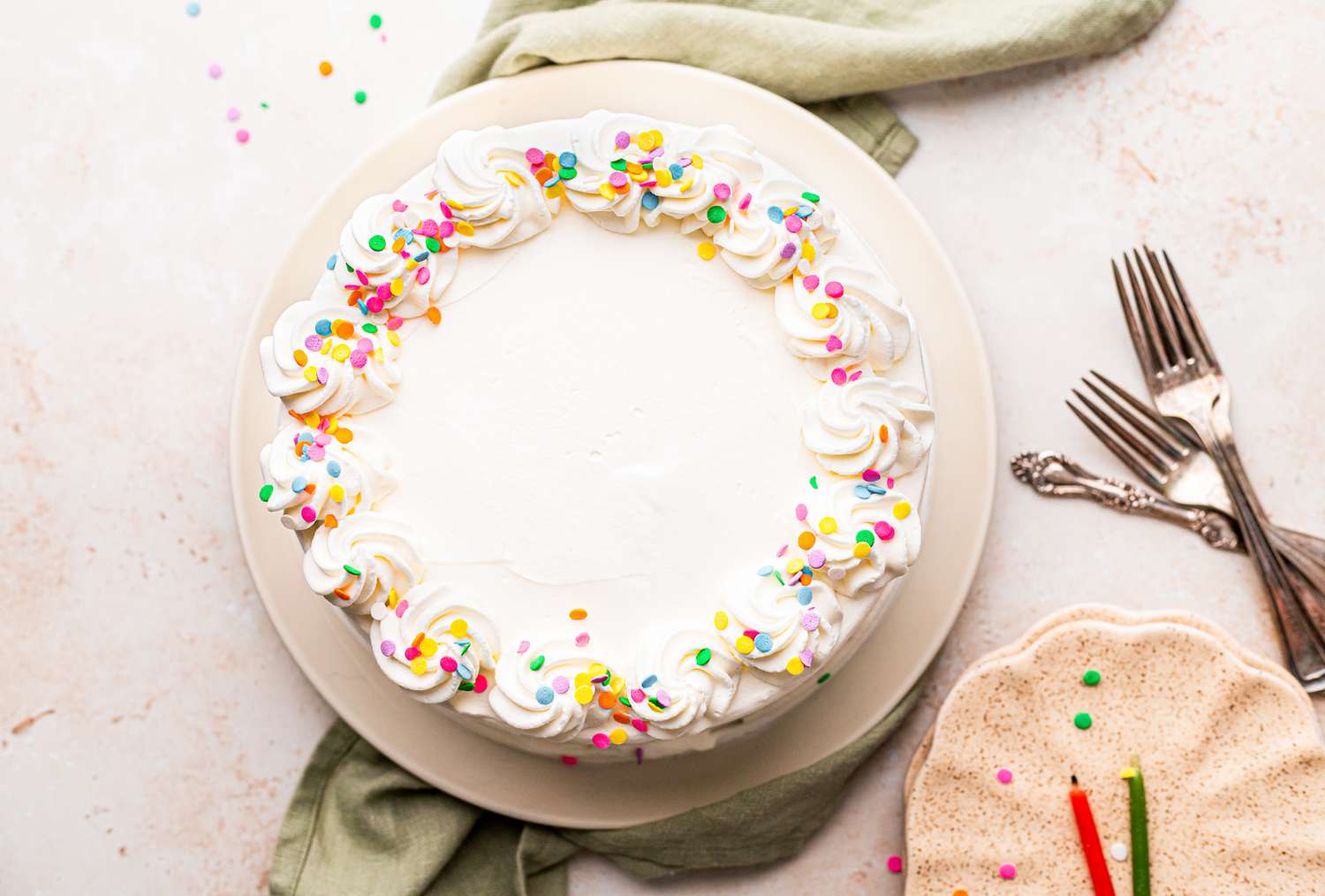 Ice Cream Cake on Plate Next to Forks and Smaller Plates with a Candle on It 
