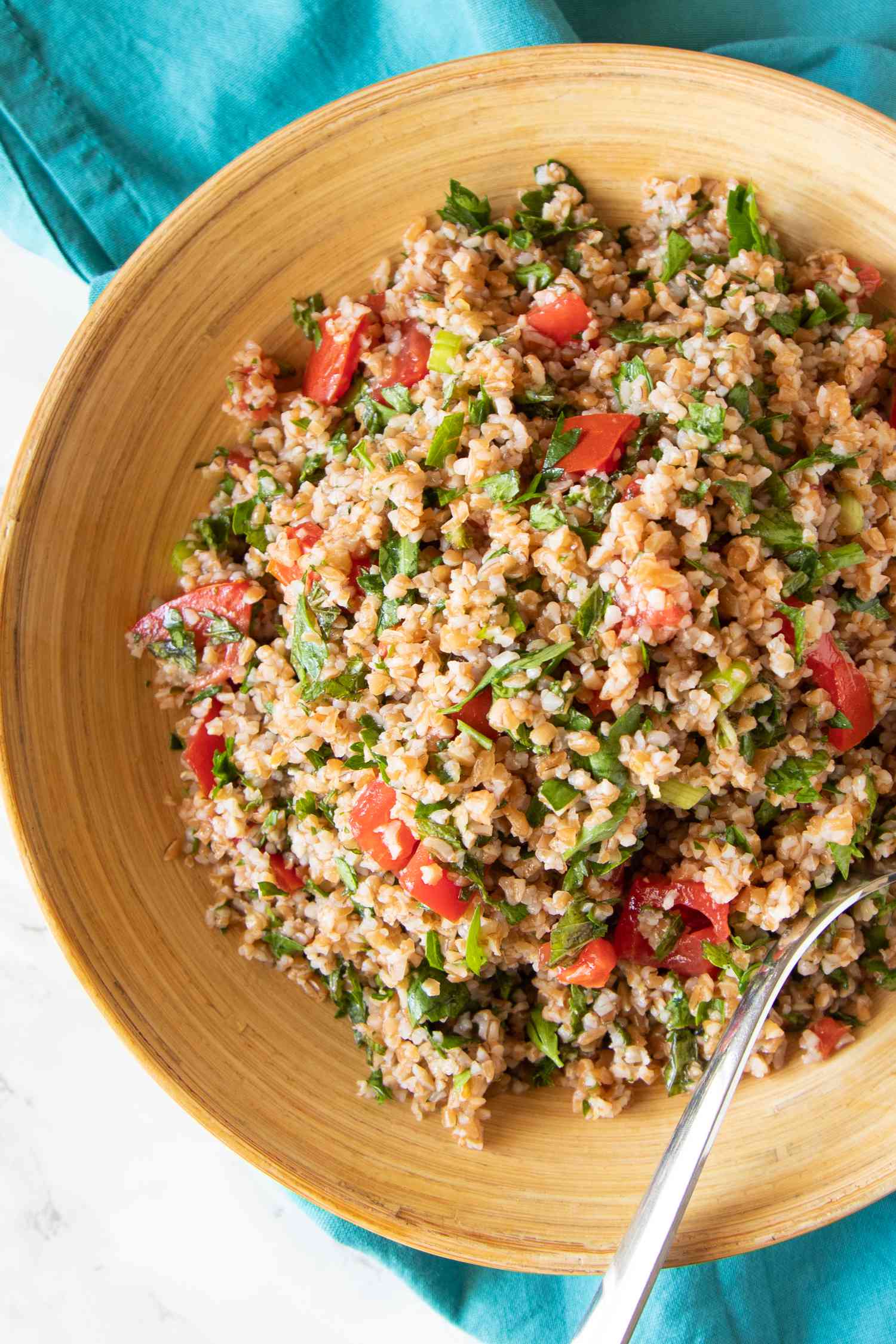 Tan bowl with tabbouleh and a spoon.