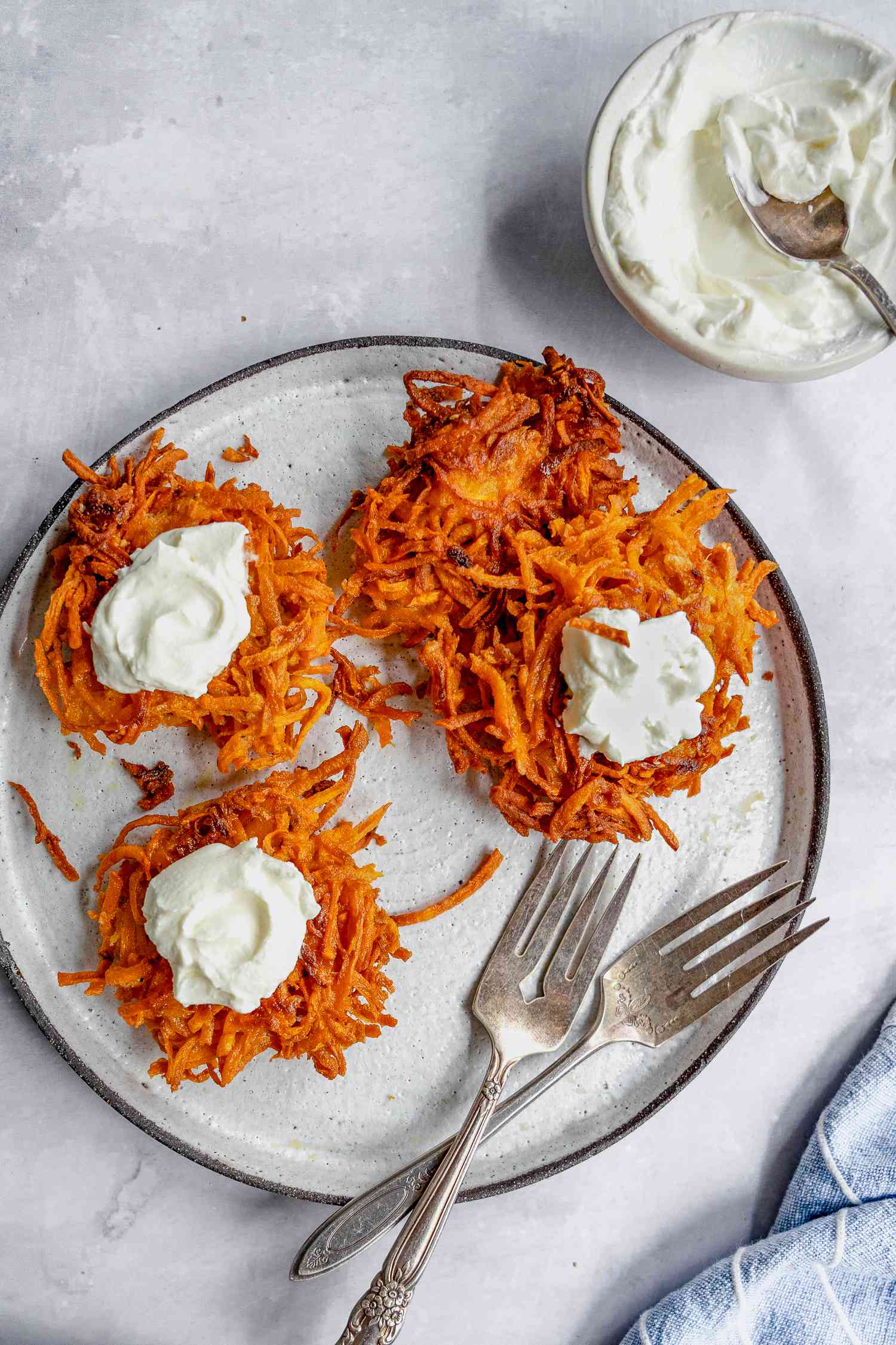 Plate of Sweet Potato Latkes Topped with Dollops of Sour Cream and Next to It, a Small Bowl with More Sour Cream