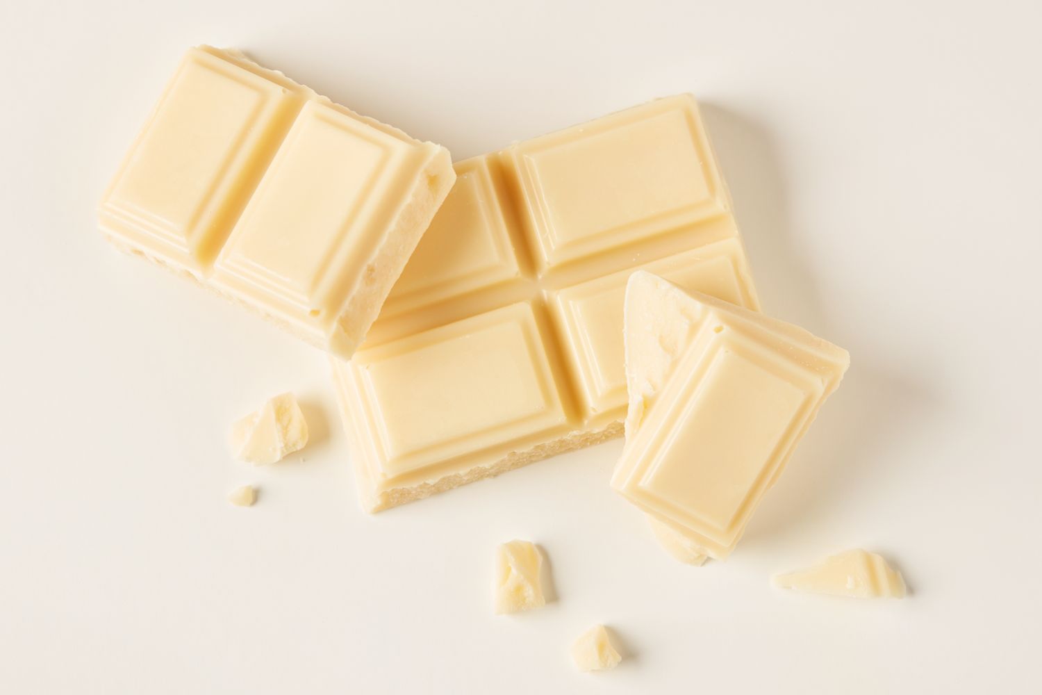 A few pieces of broken white chocolate lying on a flat surface