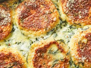Closeup of a baked breakfast casserole with a cheese crust and visible ingredients like spinach and toasted toppings