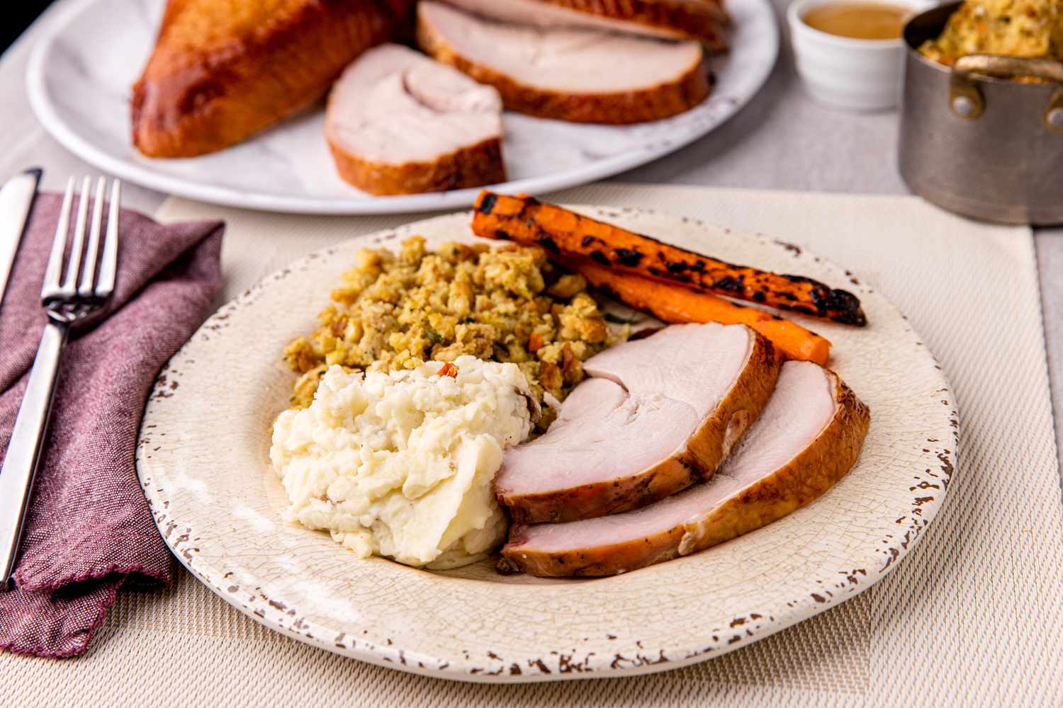 A plate with two slices of apple and sage-brined smoked turkey breast served with vegetable sides.