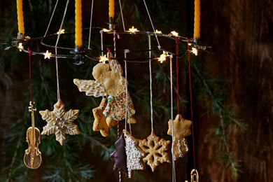 Decorative cookies hanging from a circular frame alongside candles and small star lights in a festive arrangement