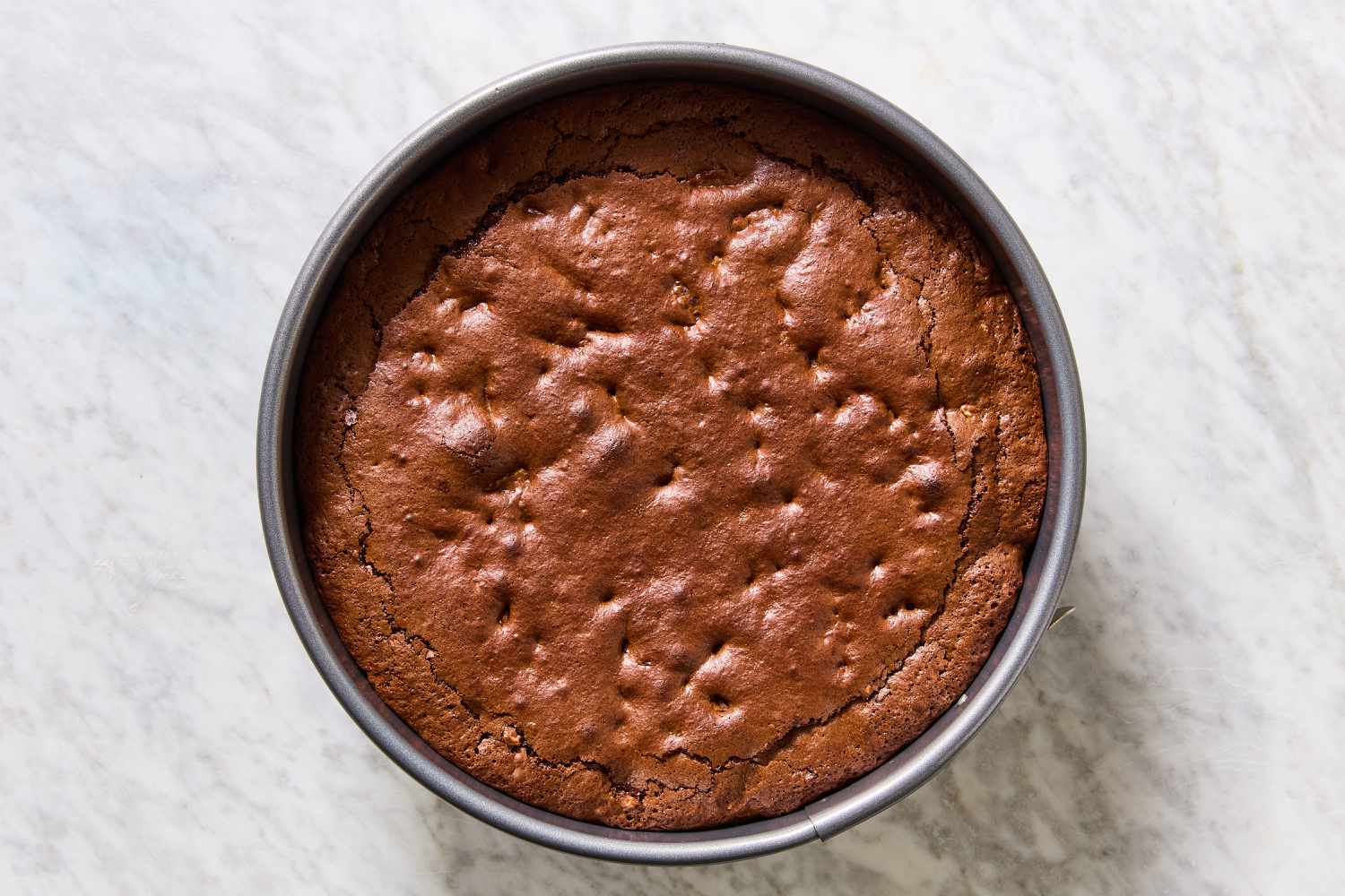 Overhead view of a springform pan showing the baked brownie batter before cooling and deflating for Mississippi Mud Pie recipe