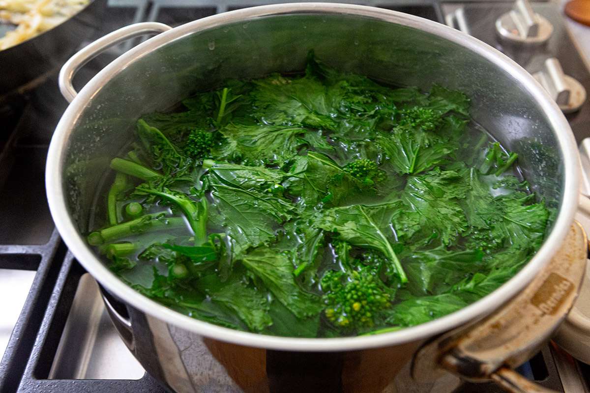 A pot of water with rabe inside.