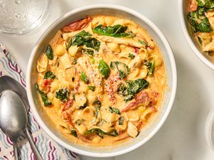 Overhead view of a white bowl of Marry Me Chicken Soup with a two spoons and a napkin to the left
