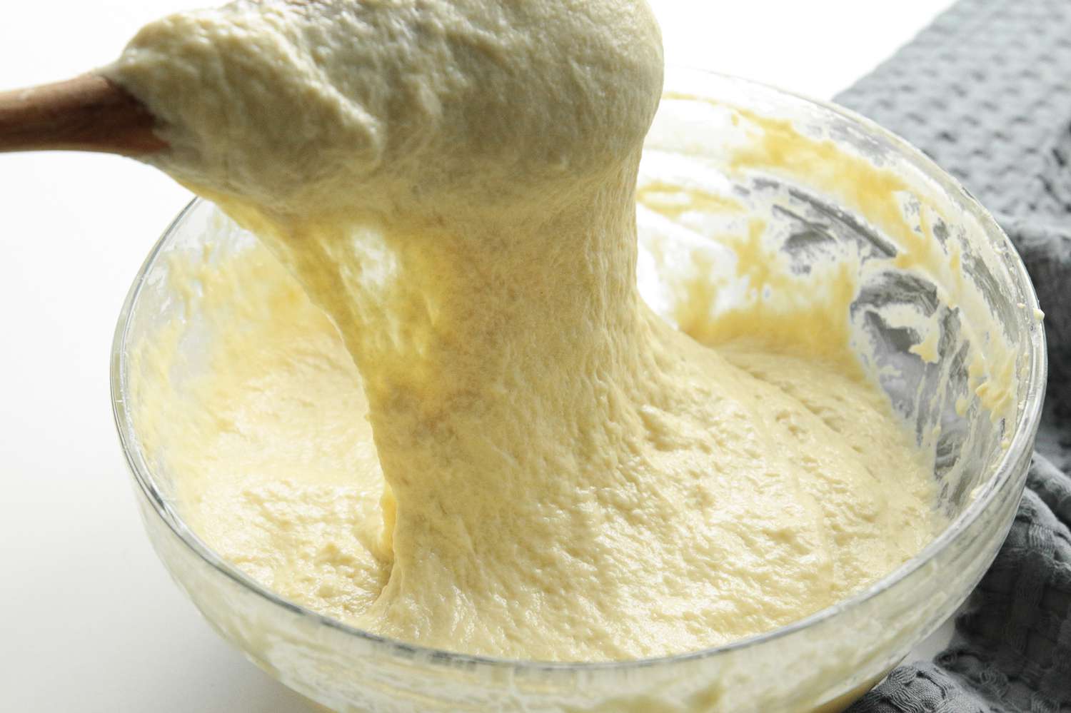 Sticky Spätzle Dough Pulled Up from a Bowl Using the Wooden Spoon