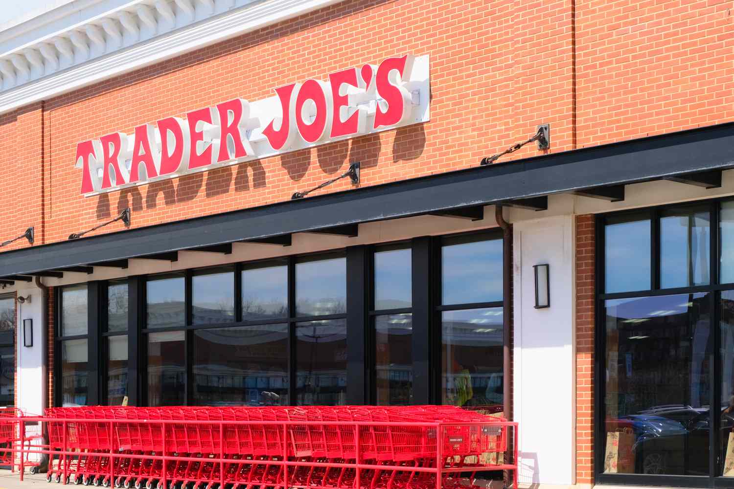 A Trader Joe's storefront showing a line of red shopping carts out front