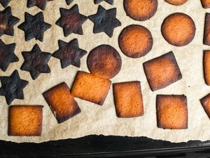 A baking sheet with overcooked cookies of various shapes on parchment paper
