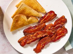 Plate with cooked bacon and toasted bread slices