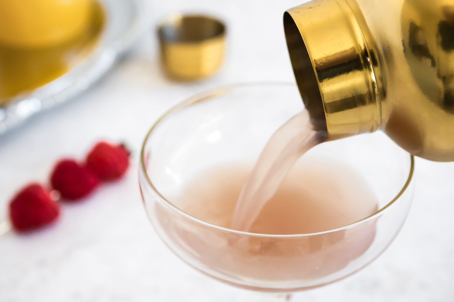French Martini Poured into a Glass with Raspberries in Background