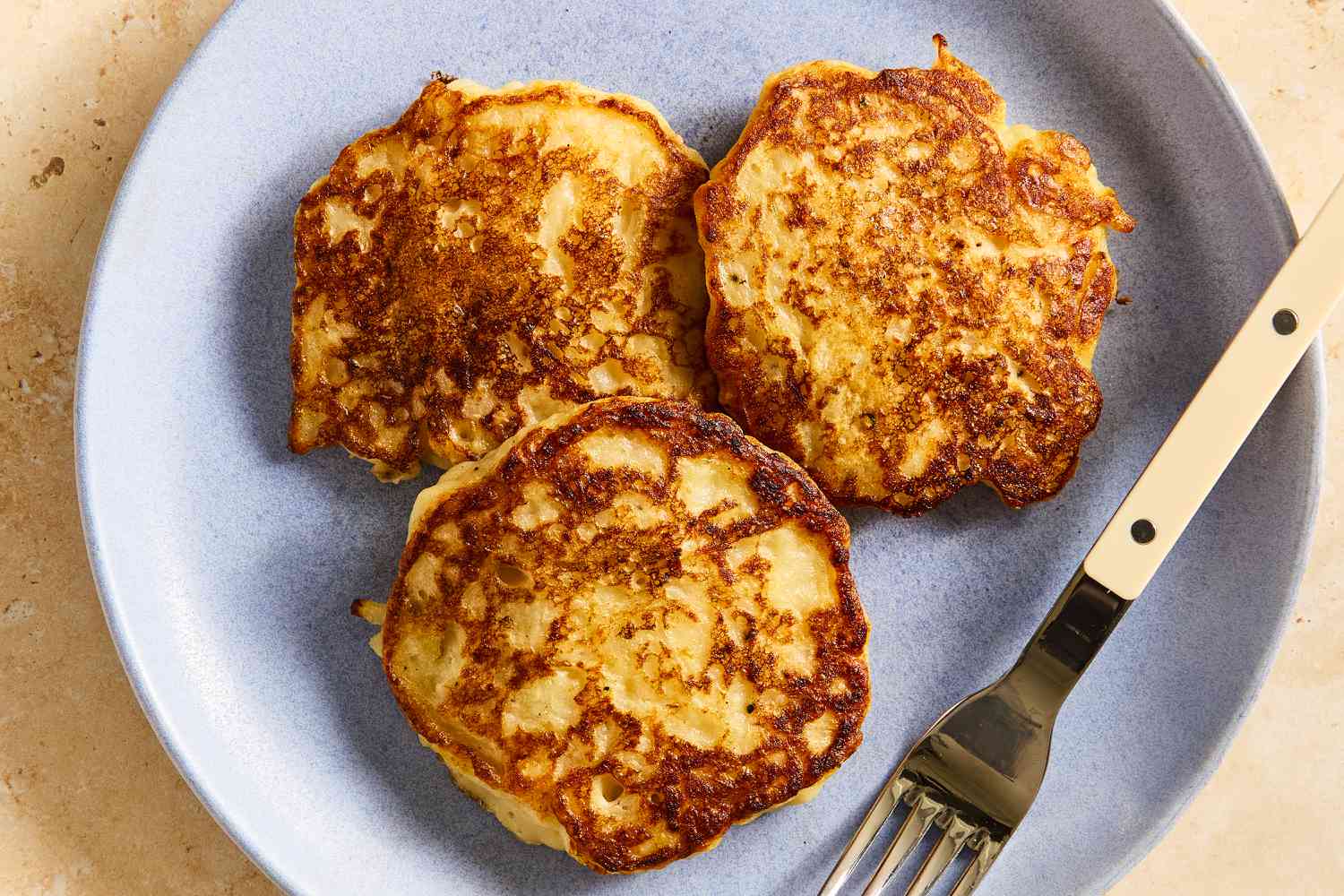 Overhead view of a plate of Irish Boxty with a fork on a stone countertop