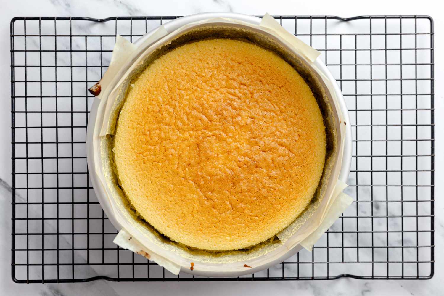 Baked Japanese Cheesecake Resting in Cake Pan on a Cooling Rack