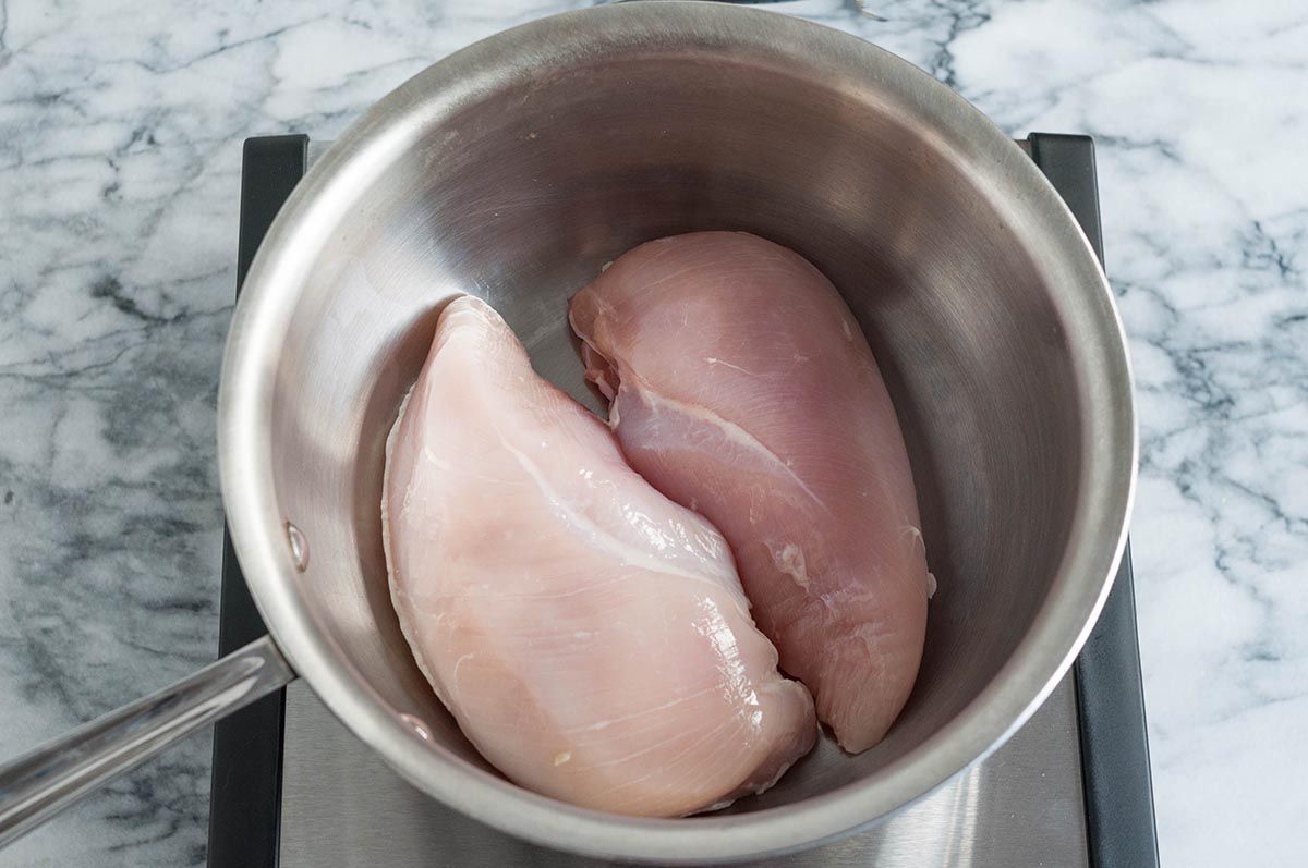 Two boneless, skinless chicken breasts in a saucepan