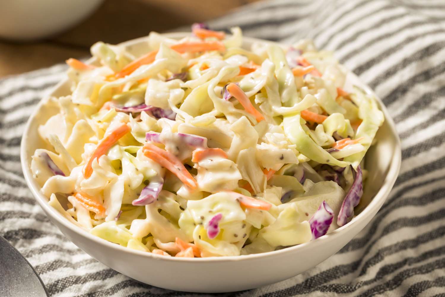 A bowl of coleslaw on striped napkin. 