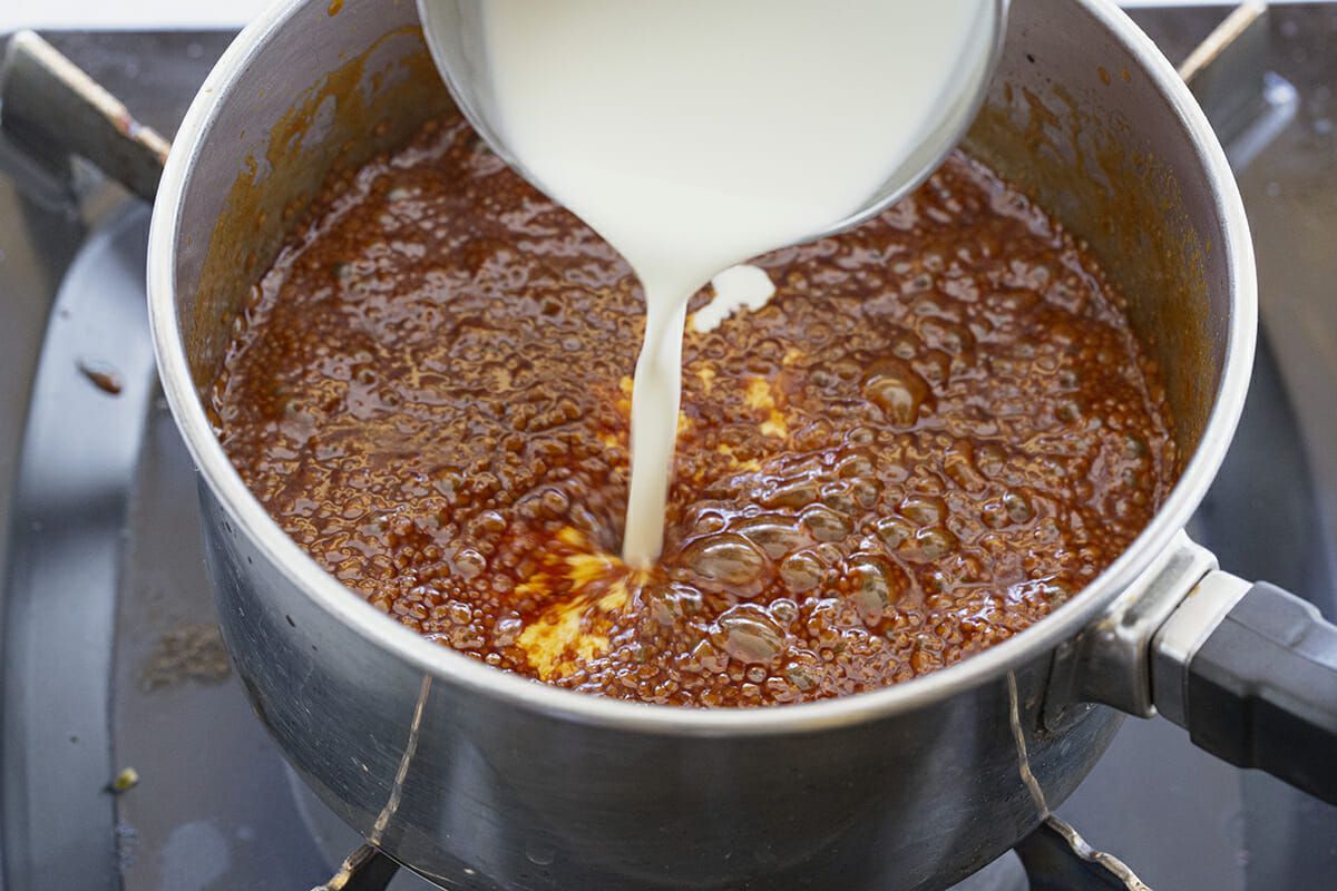 Cream poured into a pot of caramelized sugar to make caramel sauce.